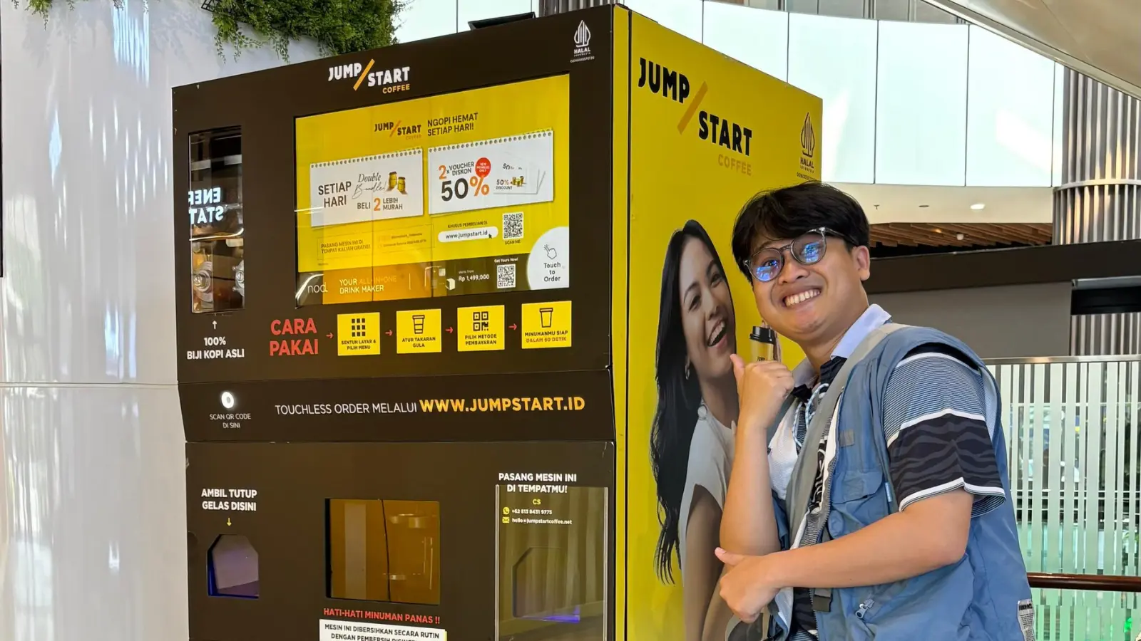 Seorang pria tersenyum di depan mesin kopi JumpStart di AEON Mall Jakarta Garden City.
